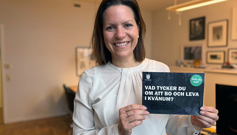 Glad kvinna håller upp ett vykort.