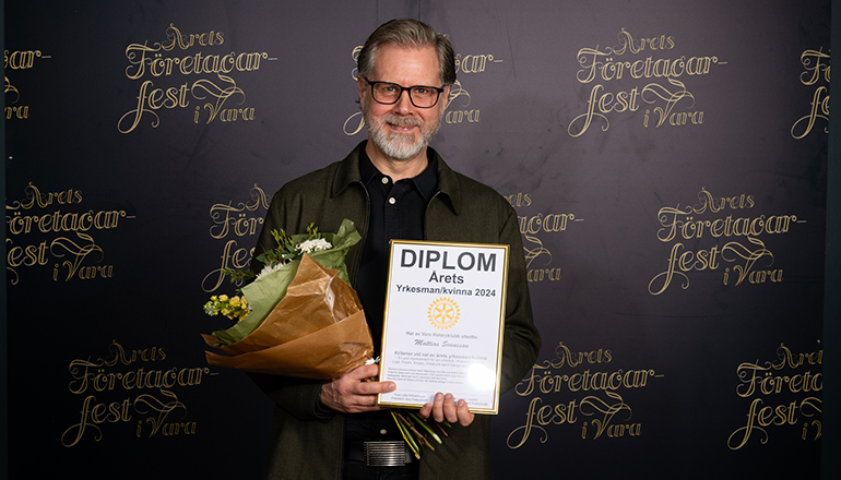 En man med blommor och diplom i händerna.