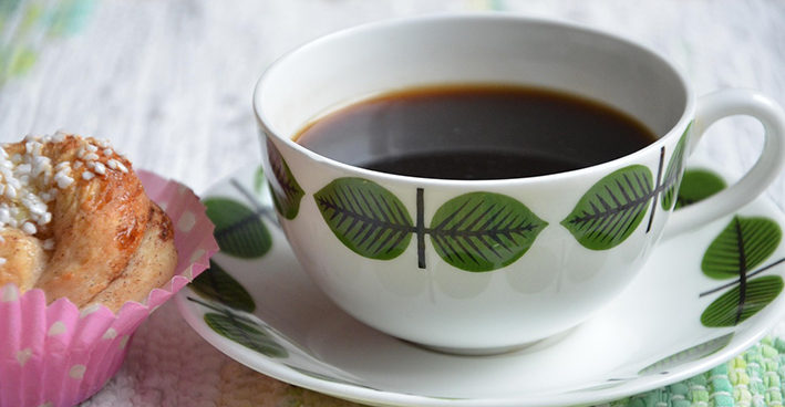 Kaffekopp på fat och en kanelbulle.