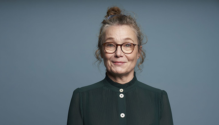 Kvinnan Ann-Marie Körling med uppsatt hår ler mot kameran