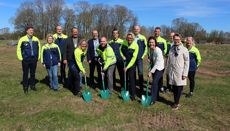 Många personer i varseljackor står bakom fyra personer som håller i var sin spade