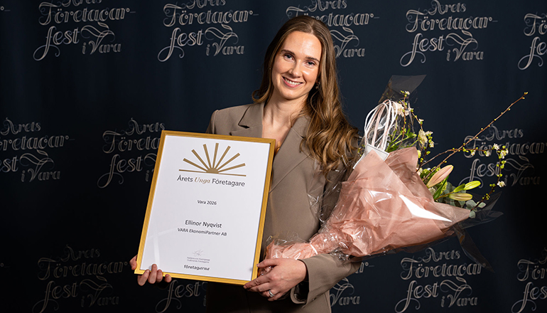 En kvinna med diplom och blommor i händerna.