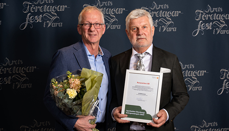 Två män med diplom och blommor i händerna.