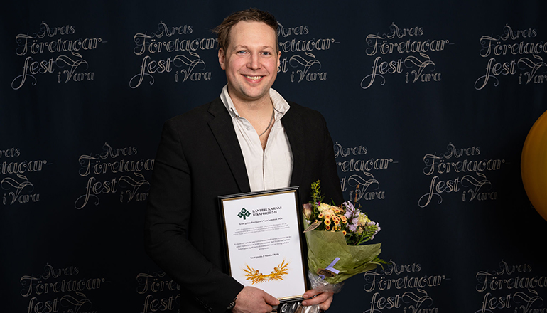 En man med blommor och diplom i händerna.