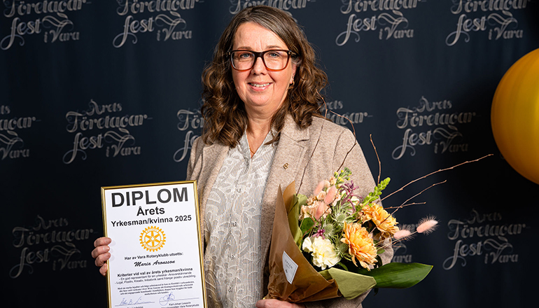 En kvinna med blommor och diplom i händerna.