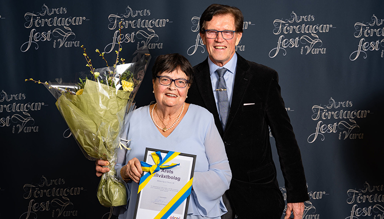 En man och en kvinna med blommor och diplom i händerna.