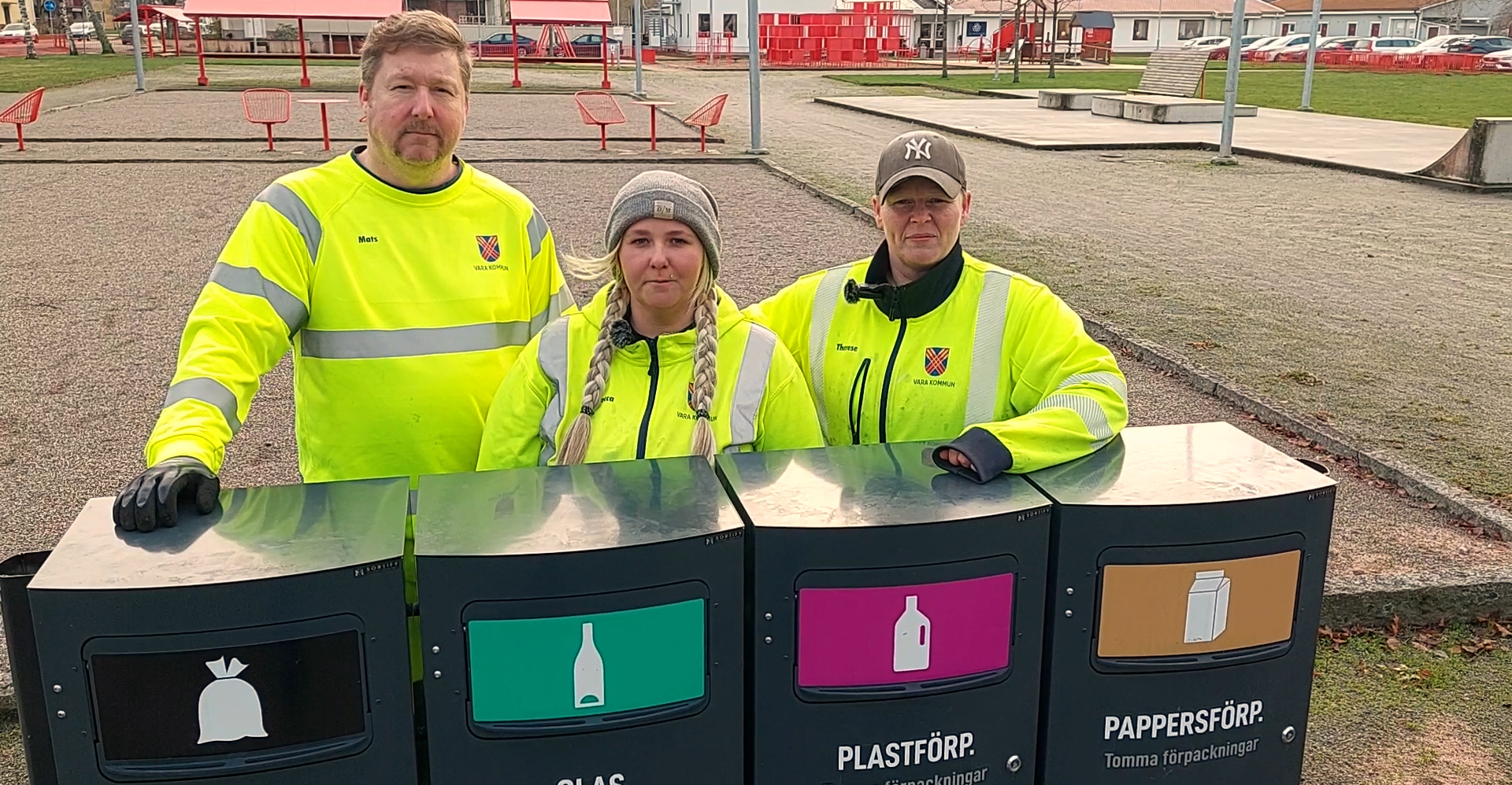 Tre personer i varselkläder står bakom källsorteringskärl
